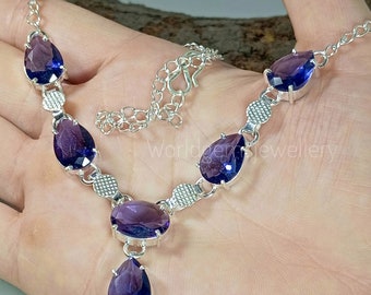 May include: A silver necklace with a teardrop-shaped pendant and five purple gemstones. The necklace has a silver chain with a lobster clasp.