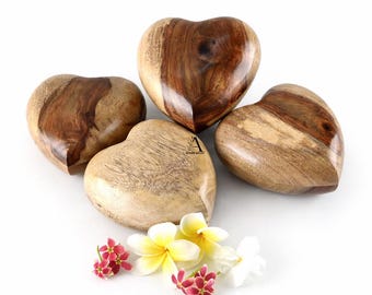 Puede incluir: Cuatro objetos de madera en forma de corazón con diferentes patrones de vetas. Los corazones están dispuestos sobre una superficie blanca, acompañados de pequeñas flores con pétalos amarillos y rojos. Los tonos de madera varían de marrón claro a oscuro.