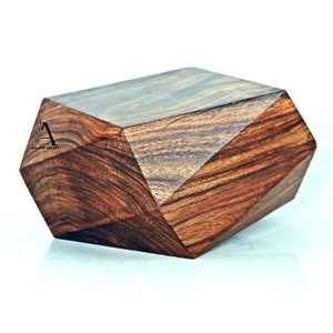 Op de afbeelding: Een geometrische houten doos met een donkerbruine houtnerf afwerking. De doos heeft een uniek, facetgeslepen ontwerp.