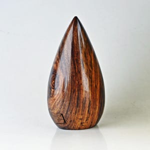 Puede incluir: Un jarr&oacute;n de madera en forma de l&aacute;grima con veta de madera marr&oacute;n oscuro y marr&oacute;n rojizo. El jarr&oacute;n est&aacute; pulido y tiene un acabado liso.