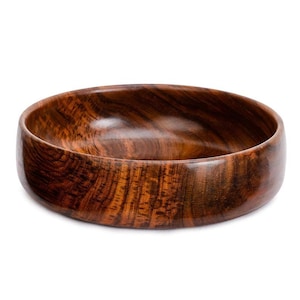 May include: A large, round wooden bowl with a dark brown wood grain. The bowl is made of a single piece of wood and has a smooth, polished finish.