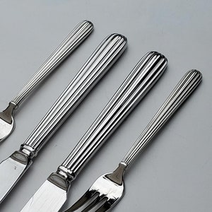 May include: Four pieces of silver cutlery, including two knives and two forks. The knives have serrated edges and the forks have three tines.
