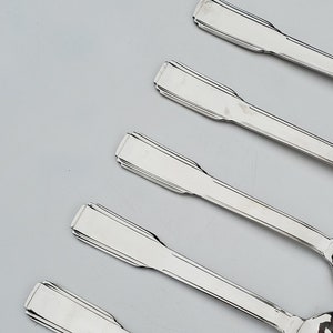 May include: Five silver spoons with ornate handles. The spoons are arranged in a row, with the handles pointing to the right. The spoons are all the same size and shape.