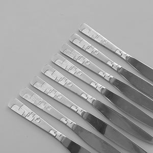 May include: A set of eight silver dinner knives with a decorative pattern on the handle.