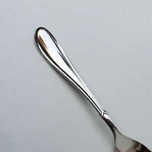 May include: A silver teaspoon with a rounded bowl and a slightly curved handle.