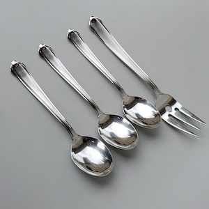 May include: Four silver utensils, including three spoons and one fork, with ornate handles. The spoons have a rounded bowl shape, while the fork has four tines.