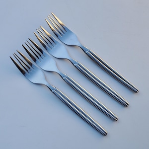 May include: Four silver forks with a textured handle. The forks are arranged in a row, with the tips of the forks pointing to the right.