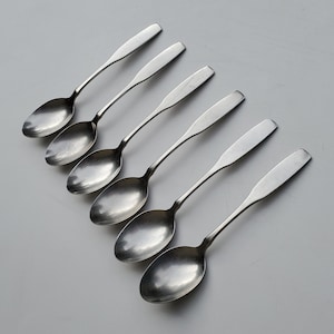 May include: Six silver spoons with rounded bowls and long handles. The spoons are arranged in a row, with the handles pointing to the right.
