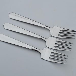 May include: Three silver forks with a pointed handle and four tines. The forks are arranged in a row, with the handles pointing to the right.