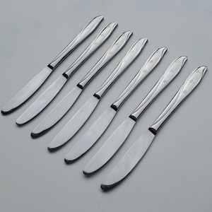 May include: Set of eight silver dinner knives with a starburst design on the handle.