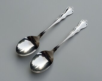 May include: Two silver spoons with ornate handles and a polished finish.
