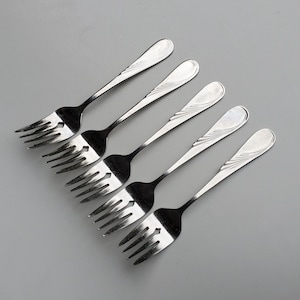 May include: Five silver forks with ornate designs on the handles. The forks are arranged in a fan shape, with the tips of the forks pointing towards the bottom of the image.