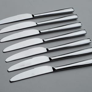 May include: A set of seven silver dinner knives with a polished finish.