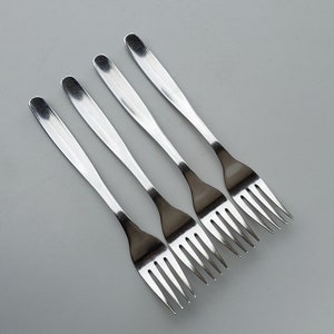 May include: Four silver forks with a polished finish. The forks are arranged in a row, with the tines pointing to the right.