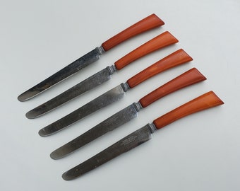 May include: Five vintage butter knives with brown plastic handles. The knives have silver blades with the words "Stainless Steel Made in England" etched on them.