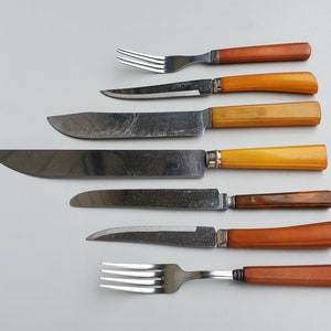 May include: Set of six vintage cutlery pieces with brown and yellow plastic handles. The set includes five knives and one fork.