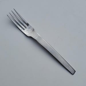 May include: A silver fork with a long, thin handle. The fork has four tines and a smooth, polished finish.