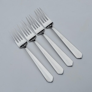 May include: Four silver forks with a simple, elegant design. The forks have a tapered handle and a smooth, polished finish.