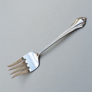 May include: A silver fork with an ornate handle. The fork has four tines and a smooth, polished finish.