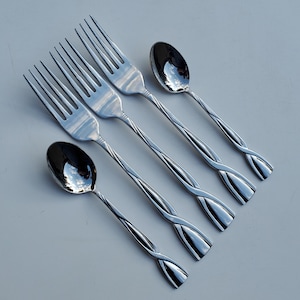 May include: A set of stainless steel silverware including three forks and two spoons. The handles have a twisted design, and the utensils reflect the surrounding environment. The silverware is arranged on a light gray surface.