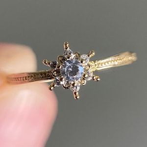 Peut inclure: Une bague en or avec un motif en forme d'étoile ornée d'un cristal transparent au centre. La bague a un design délicat et complexe.