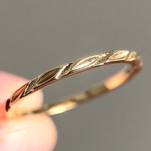 Peut inclure: Une fine bague en or avec un design texturé délicat. La bande est lisse et polie, avec un léger éclat.