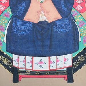 Pode incluir: Pintura detalhada de uma figura em traje asi&aacute;tico tradicional. A figura usa uma t&uacute;nica azul escura com detalhes azuis ornamentados e um top rosa claro. A parte inferior apresenta uma saia branca com padr&otilde;es florais rosa, contra um fundo colorido.