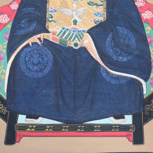 Pode incluir: Uma pintura detalhada de uma figura em trajes tradicionais chineses. A figura est&aacute; vestindo uma t&uacute;nica azul escura com padr&otilde;es circulares intrincados e detalhes dourados. A obra de arte apresenta um cinto decorativo e um fundo com motivos florais e de p&aacute;ssaros.
