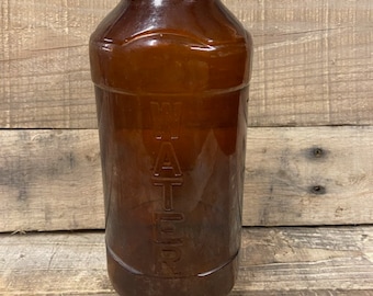 May include: A brown glass bottle with the word "WATER" embossed on the side.