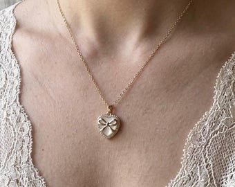 Collier à pendentif coeur doré, nœud imitation nacre, garniture en zircones cubiques
