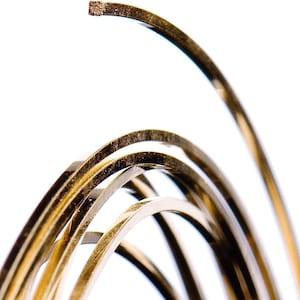 May include: Close-up of a coil of gold-colored wire. The wire is shiny and has a smooth surface. The wire is coiled in a spiral shape.
