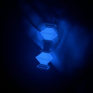 May include: A blue glowing lantern with a square shape and a decorative design. The lantern is hanging from the ceiling and is casting a soft blue light.