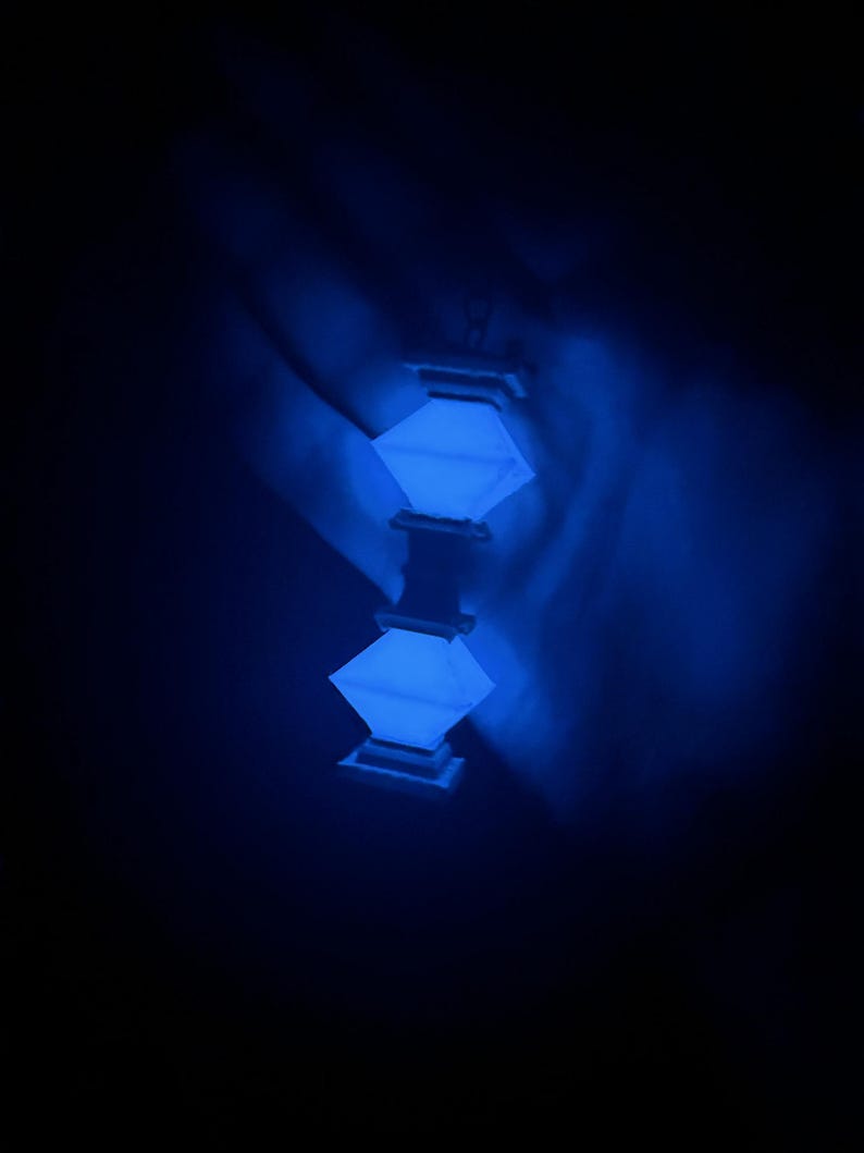 May include: A blue glowing lantern with a square shape and a decorative design. The lantern is hanging from the ceiling and is casting a soft blue light.
