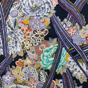 May include: A black fabric with a colourful floral pattern. The flowers are in shades of blue, red, yellow, and green. The fabric has a textured look, like it is woven with small beads.