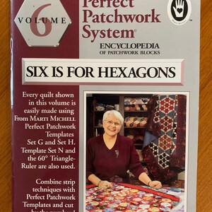 May include: Volume 6 of the Perfect Patchwork System encyclopedia of patchwork blocks, featuring a woman holding a quilt made with hexagons. The book cover features the title "Six is for Hexagons".