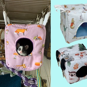 May include: Three small pet habitats. One is pink with a fox and mushroom pattern, with a small animal peeking out. The other two are cube-shaped, one with a Peter Rabbit design and the other with forest animals.