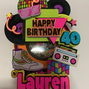 May include: A colorful 80s-themed birthday cake topper with a roller skate, boombox, Rubik's cube, and disco ball. The topper includes the text "Happy Birthday 40" and the name "Lauren" in bright pink.