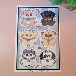 May include: A sheet of stickers featuring six cartoon dog designs. Each dog is a different color and pattern, with button details and a small bone or treat graphic. The background is a gray and white checkered pattern.