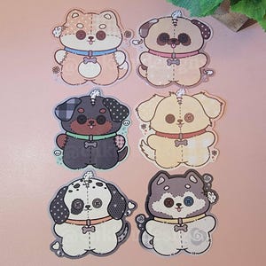 May include: Six colorful dog stickers with button eyes and stitched details. Each sticker features a different breed, including a pug, husky, and dalmatian. The stickers have a cute, handmade aesthetic, perfect for decorating notebooks or laptops.