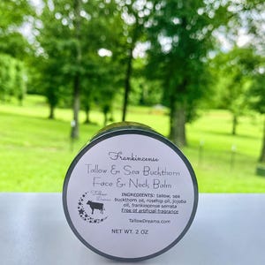 May include: A round jar of Frankincense Tallow & Sea Buckthorn Face & Neck Balm. The label includes the product name, ingredients, and the brand's logo with a cow silhouette. The jar is 2 oz.