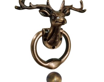 May include: A bronze door knocker shaped like a deer's head with antlers. The knocker has a round ring and a small, round, bronze ball hanging below it.