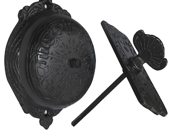 May include: Black cast iron doorbell with a decorative floral design. The doorbell has a lever on the side to ring the bell.