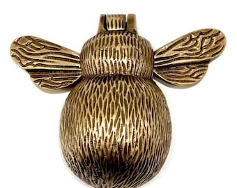 May include: A brass door knocker shaped like a bee. The bee has a textured body and wings.