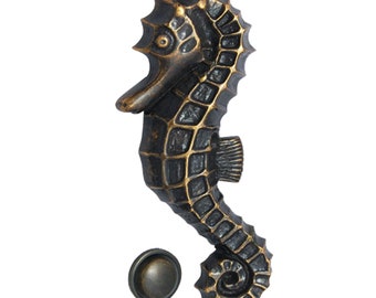May include: A bronze seahorse door knocker with a round, bronze knob. The seahorse is detailed with scales and has a curled tail.