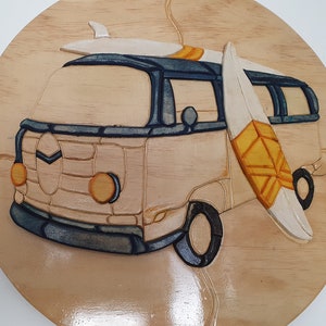 May include: A wooden wall art carving of a vintage van with two surfboards on top. The van is painted in shades of brown, blue, and yellow. The surfboards are white with yellow accents.