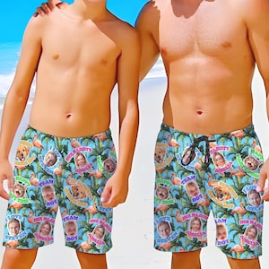 May include: Blue swim trunks with a tropical pattern featuring flamingos, palm trees, and personalized photo inserts. The trunks have a drawstring waist and include text such as "Her Majesty Amelia" and "I Love Steven".