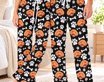 May include: Black pajama pants featuring a repeating pattern of brown poodle faces, white paw prints, and white bones. The pants have an elastic waistband with a white drawstring tie, providing a comfortable fit for lounging at home.