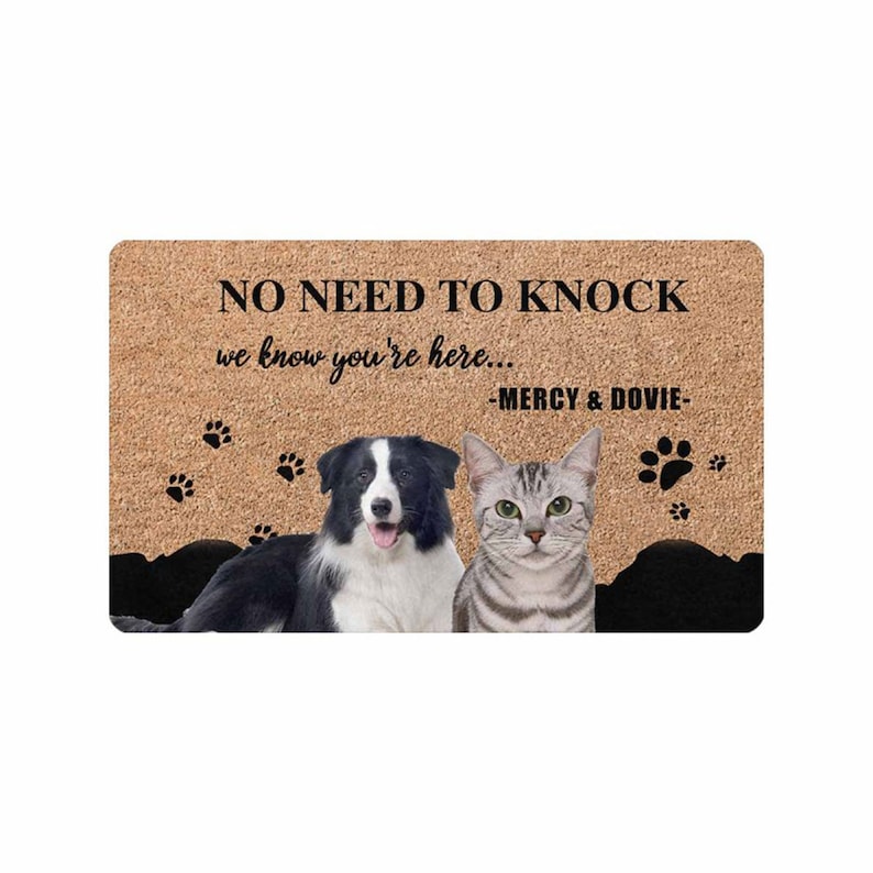 以下が含まれることがあります： 「NO NEED TO KNOCK we know you're here... -MERCY & DOVIE-」と書かれた茶色の玄関マット。黒と白のボーダーコリーと灰色の虎猫がマットの上に座っています。