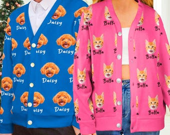 May include: A blue cardigan featuring a repeating pattern of a dog's face and the name Daisy, and a pink cardigan featuring a repeating pattern of a cat's face and the name Bella, both with white buttons and a V-neckline design.