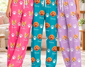 May include: Three pairs of lounge pants featuring repeating patterns of pet faces and paw prints. The pink pair displays cat faces labeled Bella, the teal pair shows dog faces labeled Daisy, and the lavender pair features cat faces labeled Bella.